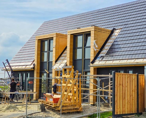 Gesloten houten gevelbekleding in natuurlijke houtkleur op nieuwbouwproject met dakkapellen